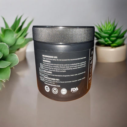 Black container with text on a gray surface with plants in the background