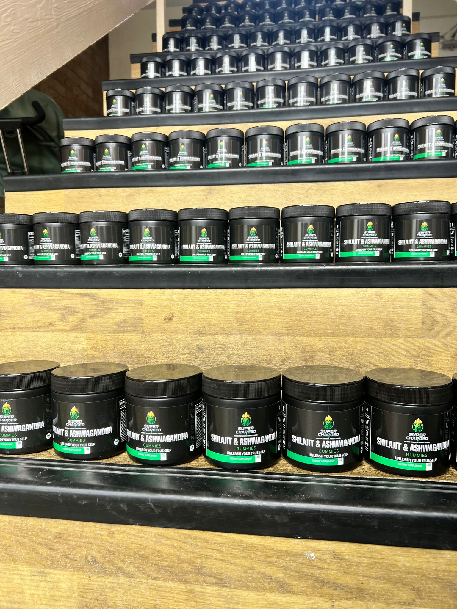Shelves with black containers labeled 'Mildred & Ashwagandha' on a wooden shelf.